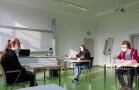 Mehrere Personen sitzen mit Abstand in Klassenzimmer