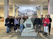 Personengruppe steht um eine steinerne Skulptur in einem Raum