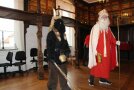 Als Nikolaus und Krampus verkleide Personen stehen in einem Raum