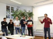 Sechs Personen stehen vor Flipchart in Seminarraum